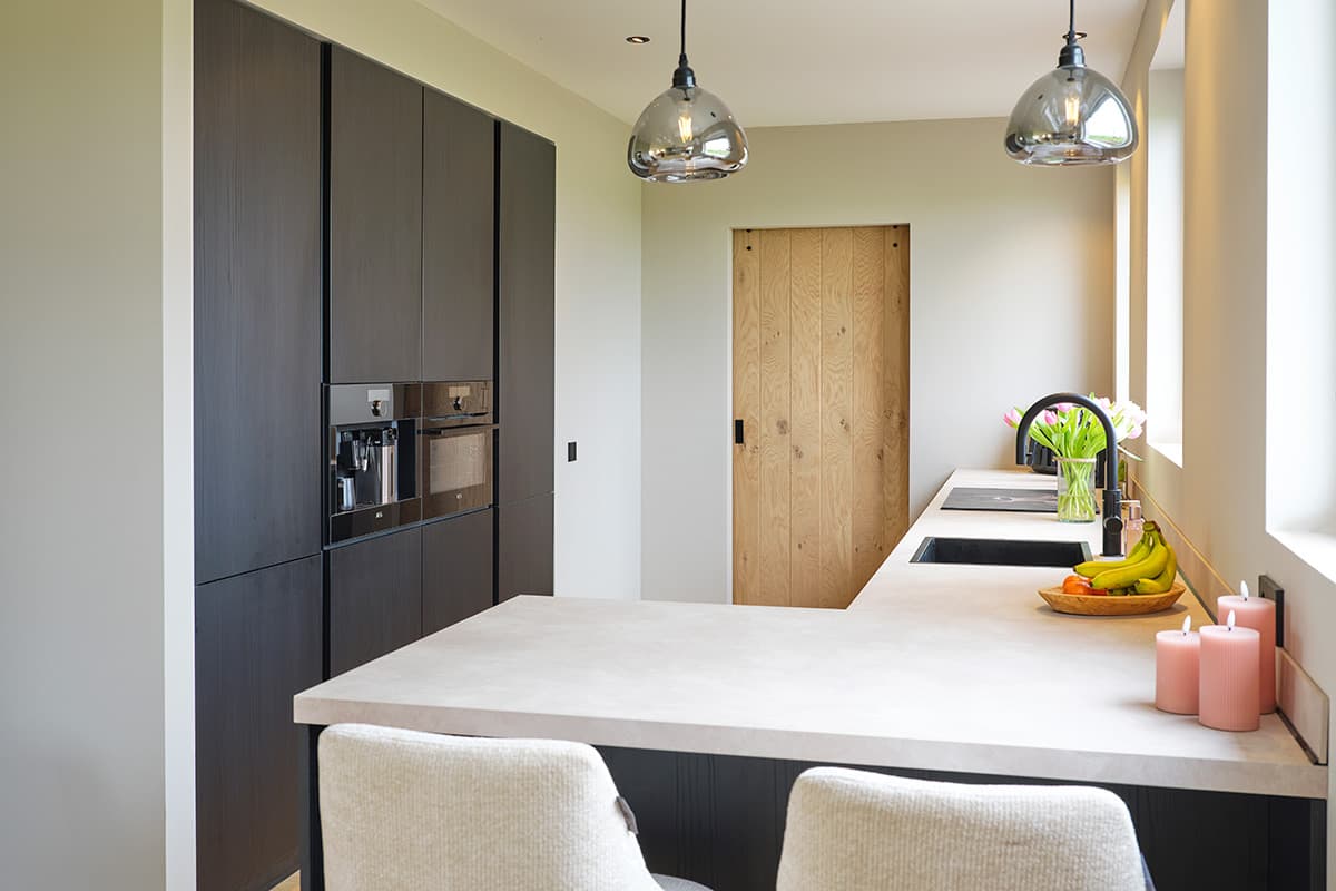 Zwarte-keuken-met-bar-en-kastenwand