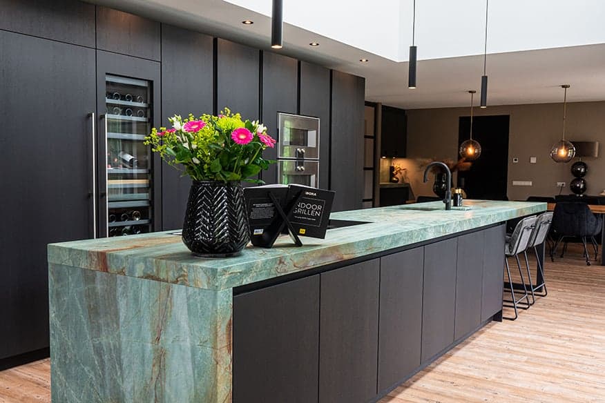 Luxe-designkeuken-met-lichtblauw-werkblad-en-donkere-fronten